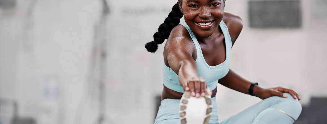 Fitnessstudio, Porträt oder schwarze Frau, die ihre Beine für ein Workout oder eine Körperbewegung für aktive Fitness dehnt. Glücklich, Sportler oder gesundes Mädchen lächelnd in Übung Ausbildung Aufwärmen für Flexibilität oder Mobilität