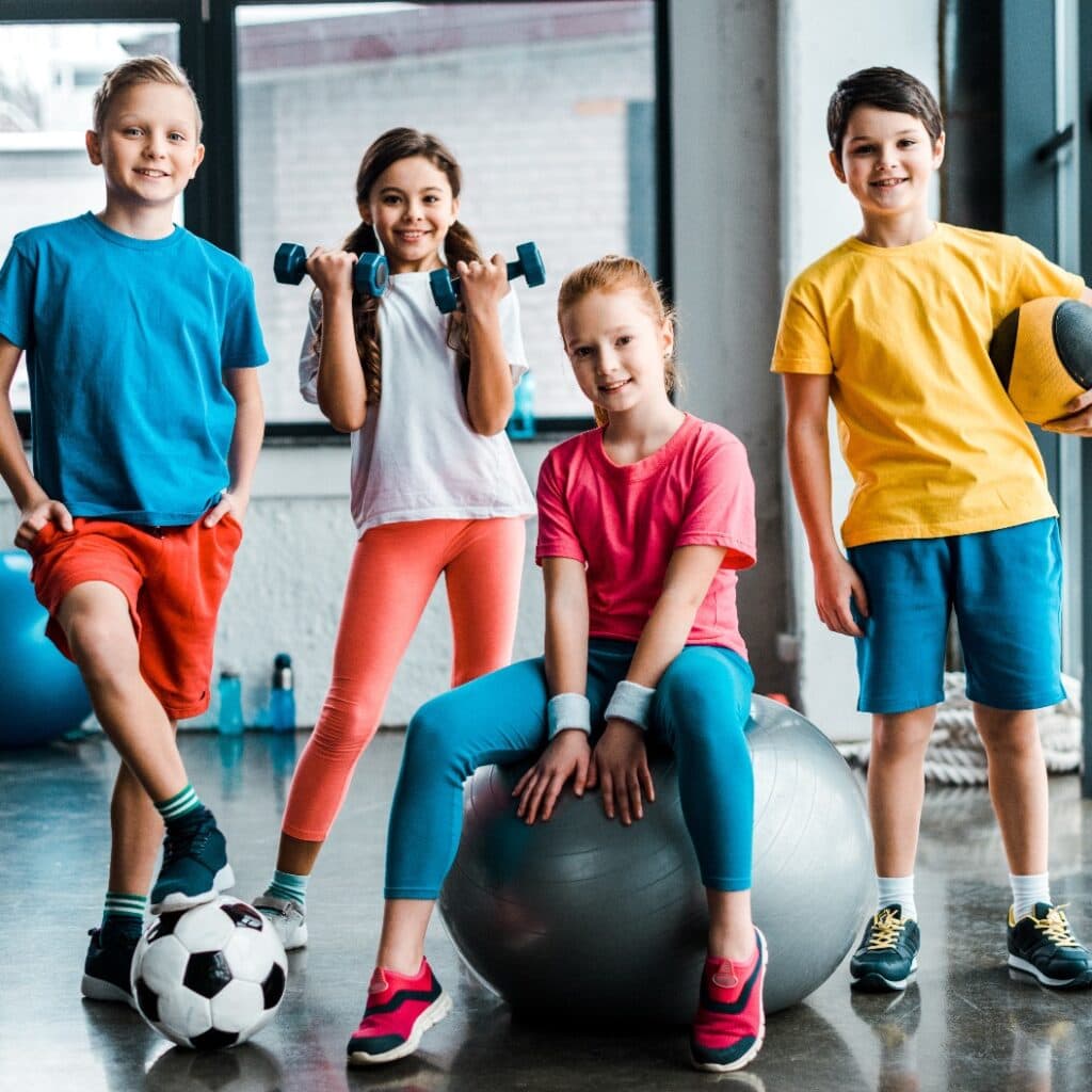 Lachende Kinder im Teenageralter posieren mit Sportgeräten